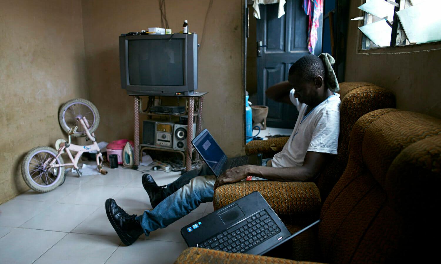A romance scammer known as “Ghost” works on his laptop in a house on April 19, 2015 in Zongo area of Accra, Ghana.  He is one of many young unemployed men here who is involved in internet scams(Per-Anders Pettersson)