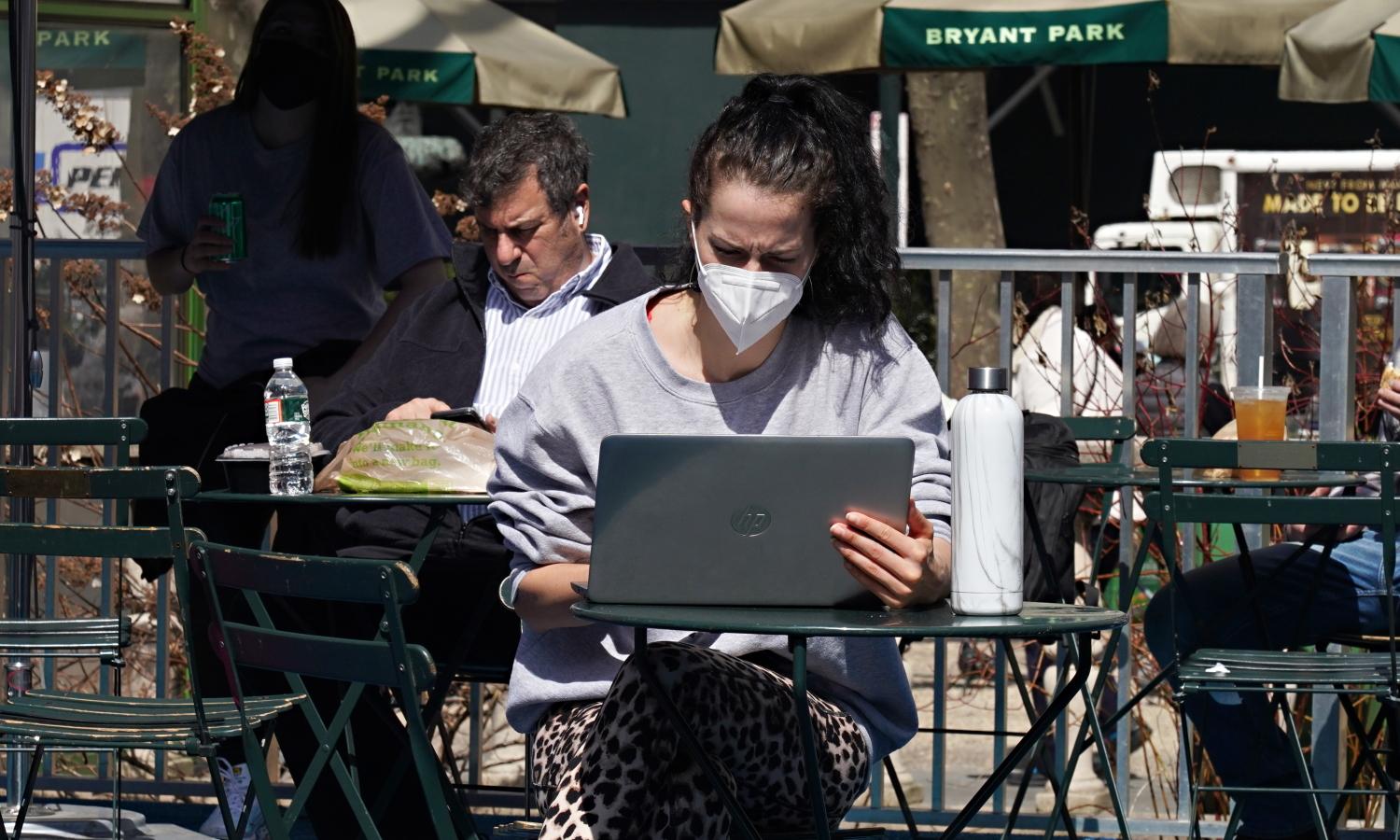 A person wearing a protective mask uses a laptop computer in Bryant Park on March 23, 2021, in New York City. Cybercriminals have taken advantage of remote-based employees who spend much of their time accessing cloud-based work applications to distribute malware via a technique known as HTML smuggling. (Cindy Ord/Getty Images)
