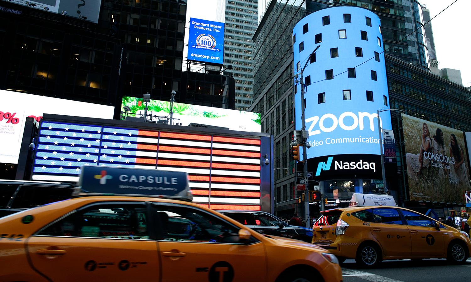 People pass by the Nasdaq building as the screen shows the logo of the video-conferencing software company Zoom on April 18, 2019, in New York City. (Photo by Kena Betancur/Getty Images)
