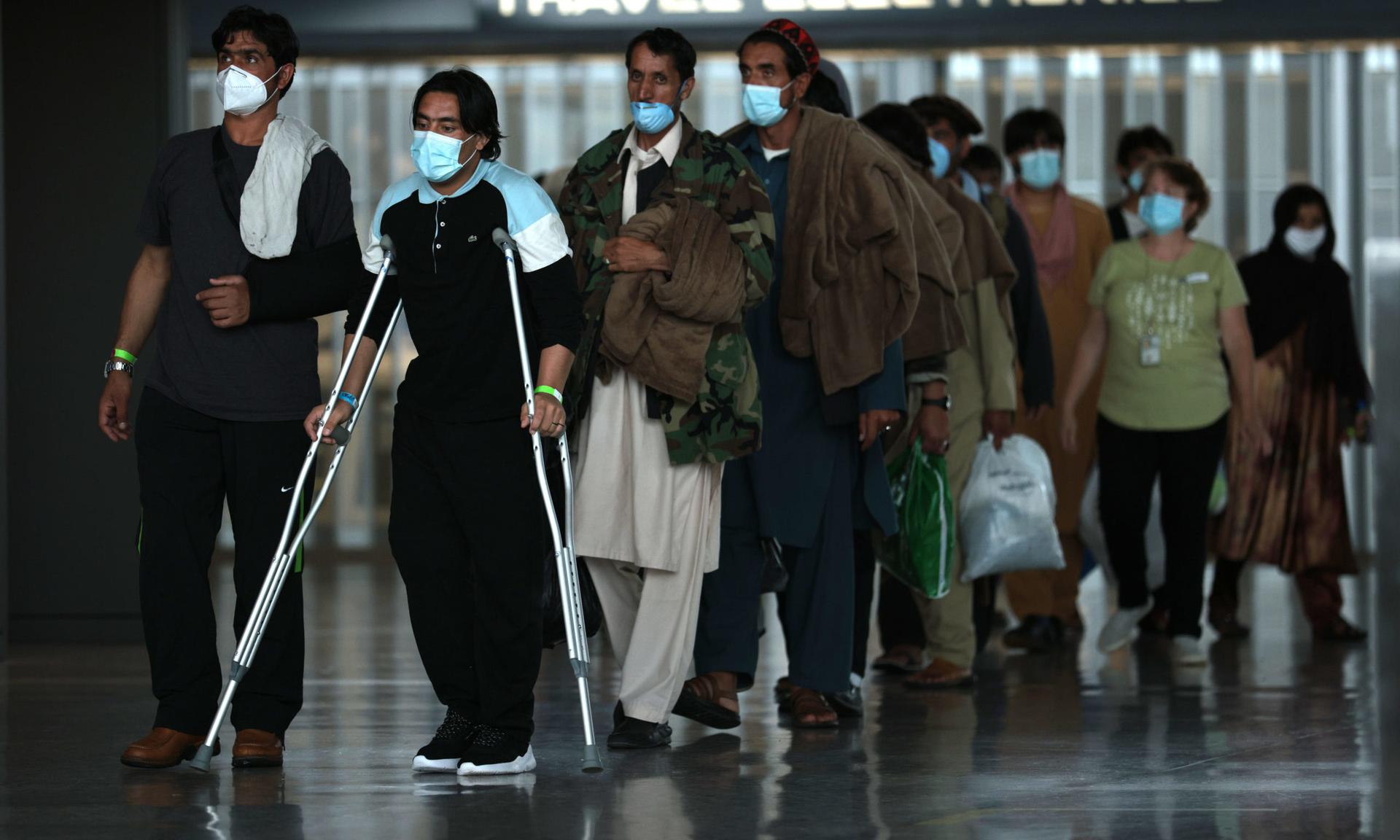 Refugees who were evacuated from Afghanistan last August walk through Dulles International Airport, from which they were later taken to a refugee processing center. (Photo by Anna Moneymaker/Getty Images)