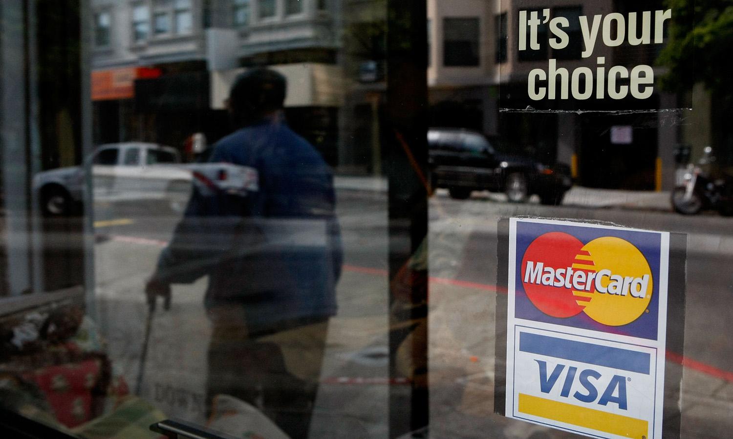 A window sticker advertising Visa and MasterCard payments hangs in a window Feb. 25, 2008, in San Francisco. (Photo by Justin Sullivan/Getty Images)