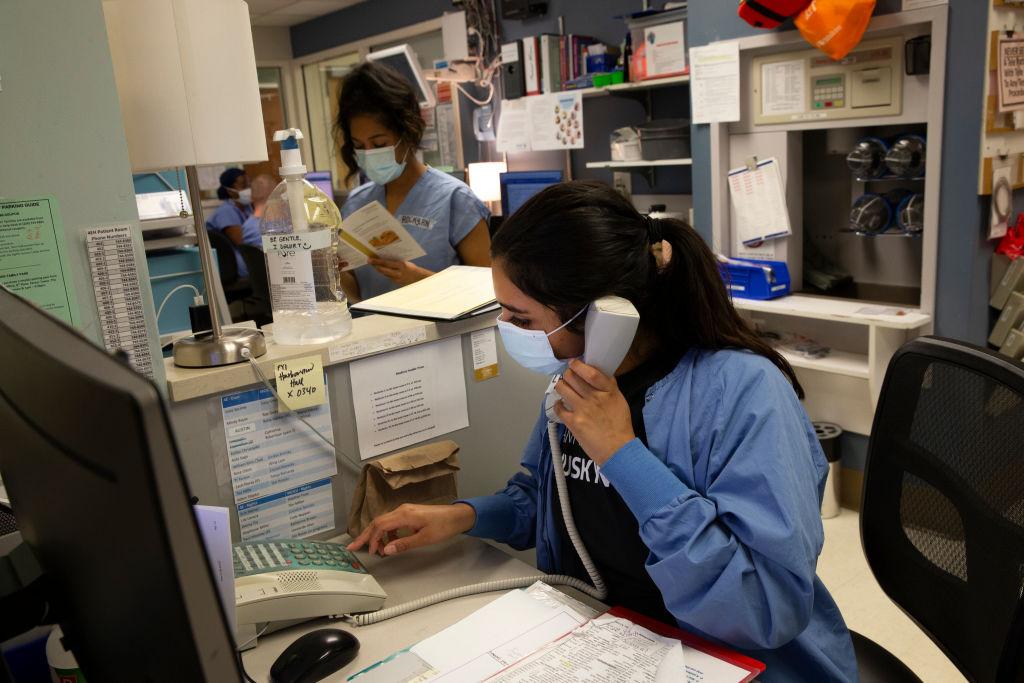 Charge nurse Liliana Palacios makes a phone call while nurse Rocky Dixon plans patient care at the nurses station in the acute care COVID unit at Harborview Medical Center on May 7, 2020, in Seattle. (Photo by Karen Ducey/Getty Images)