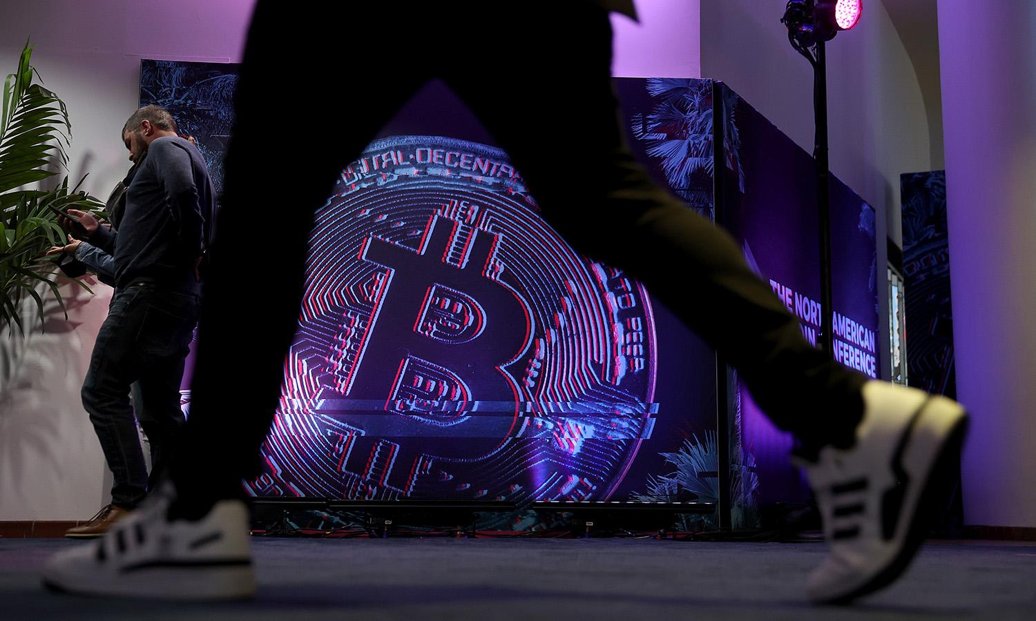 People walk through the North American Bitcoin Conference held at the James L Knight Center on Jan. 18, 2022, in Miami. The conference is a three-day event on Bitcoin, NFTs, the metaverse, Defi, DAOs, stablecoins, blockchain and more. (Photo by Joe Raedle/Getty Images)