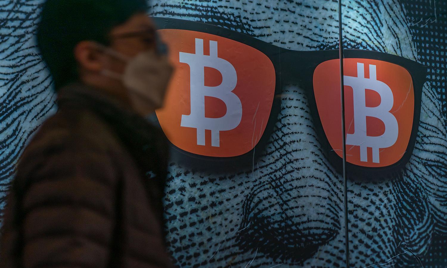Pedestrians walk past a display of cryptocurrency Bitcoin on Feb. 15, 2022, in Hong Kong. (Photo by Anthony Kwan/Getty Images)