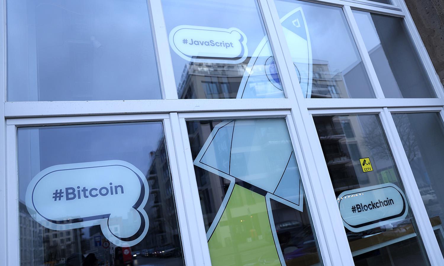 The terms &#8220;Bitcoin,&#8221; &#8220;Blockchain&#8221; and &#8220;JavaScript&#8221; are seen next to a rendition of a rocket in the window of a company that offers blockchain application services on Dec. 21, 2021, in Berlin. (Photo by Sean Gallup/Getty Images)