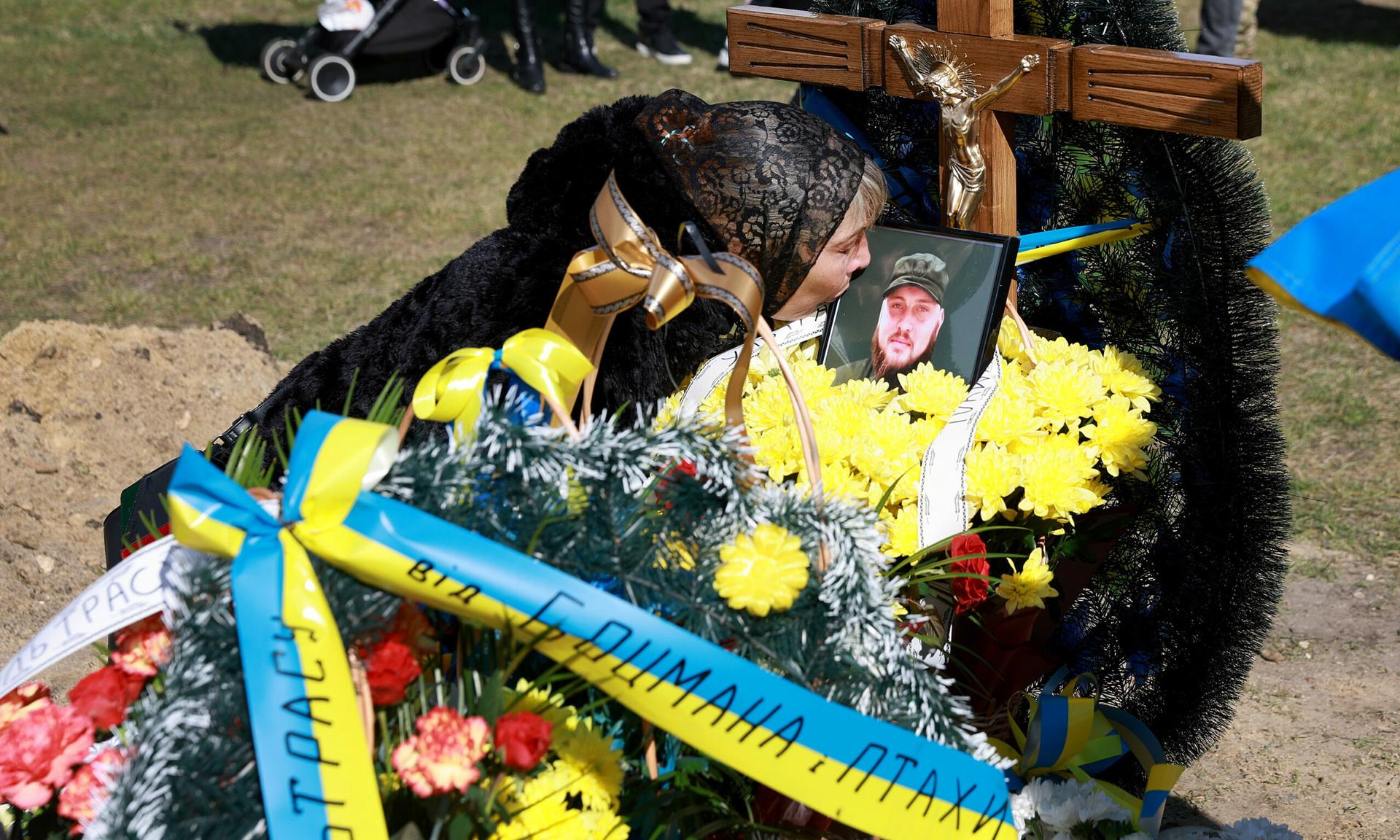Olena Siksoy kisses a picture of her son  and Ukrainian soldier Ruslan Siksoy during his burial at the Lychakiv Cemetery on April 17, 2022, in Lviv, Ukraine. (Photo by Joe Raedle/Getty Images)