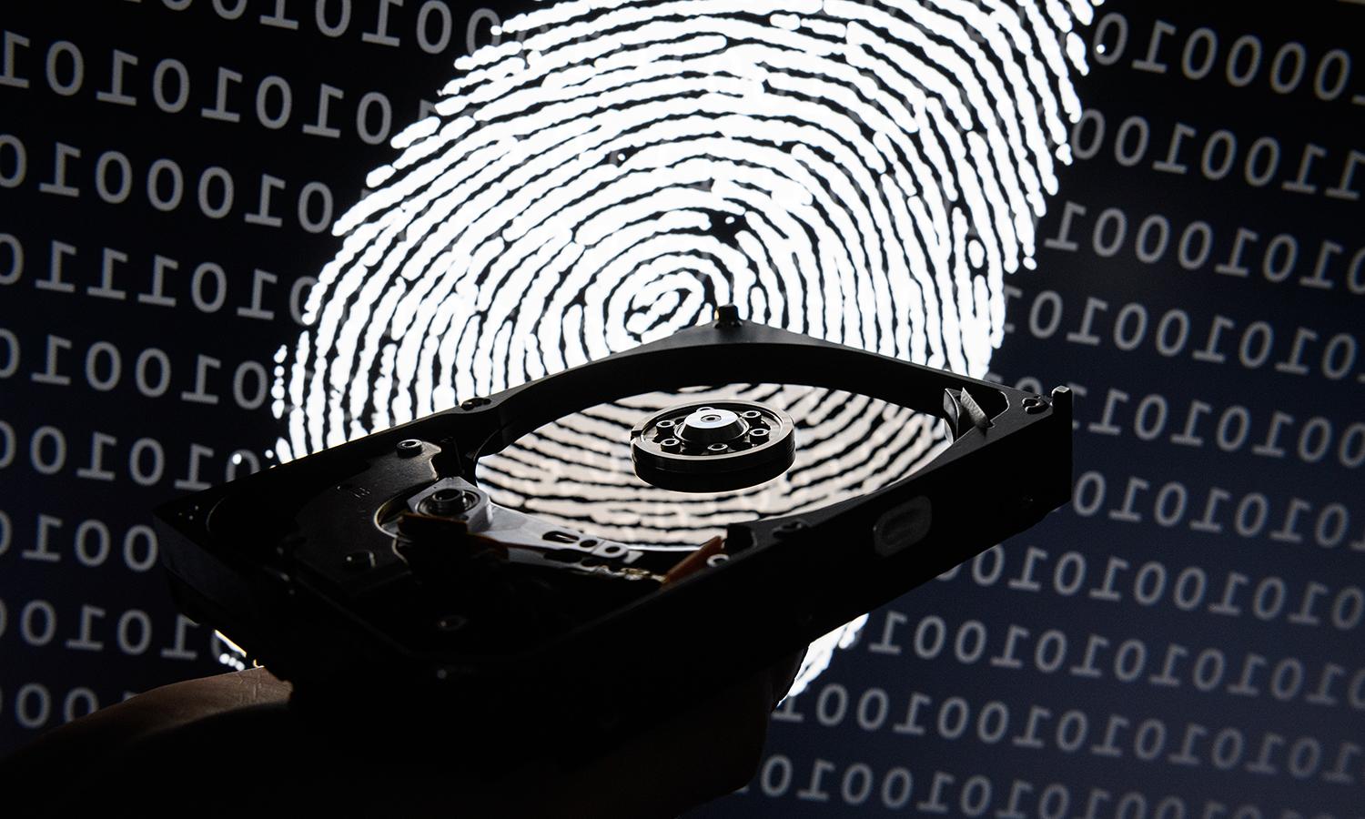 A hard drive is seen in the light of a projection of a thumbprint. (Photo by Leon Neal/Getty Images)
