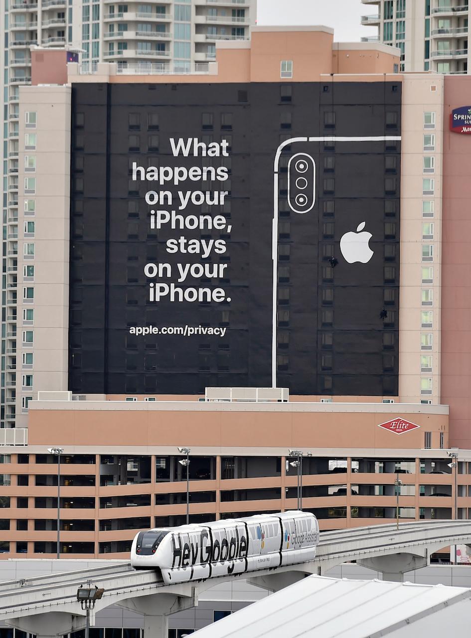 LAS VEGAS, NEVADA &#8211; JANUARY 07:  A monorail train featuring a Google ad passes by a billboard advertising Apple&#8217;s iPhone security during CES 2019 on January 07, 2019 in Las Vegas, Nevada. CES, the world&#8217;s largest annual consumer technology trade show, runs from January 8-11 and features about 4,500 exhibitors showing off their lat...