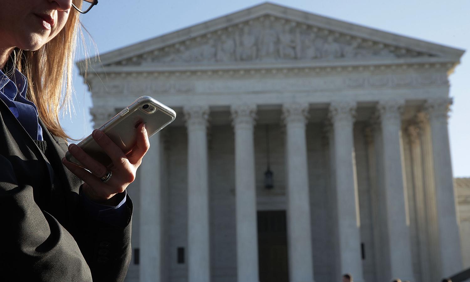 An FTC official wrote that the agency will &#8220;crack down&#8221; on companies misusing consumer data after the U.S. Supreme Court overturned Roe vs. Wade last month. Pictured: A woman checks her cell phone as she waits in line to enter the U.S. Supreme Court to view a hearing Nov. 29, 2017, in Washington. (Photo by Alex Wong/Getty Images)