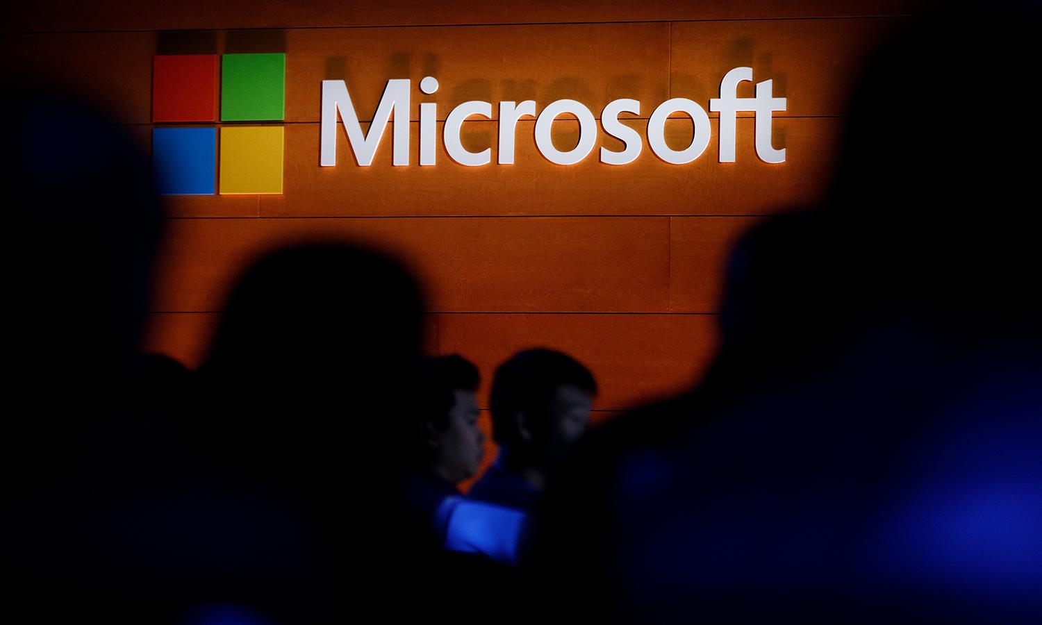 The Microsoft logo is illuminated on a wall during a Microsoft launch event