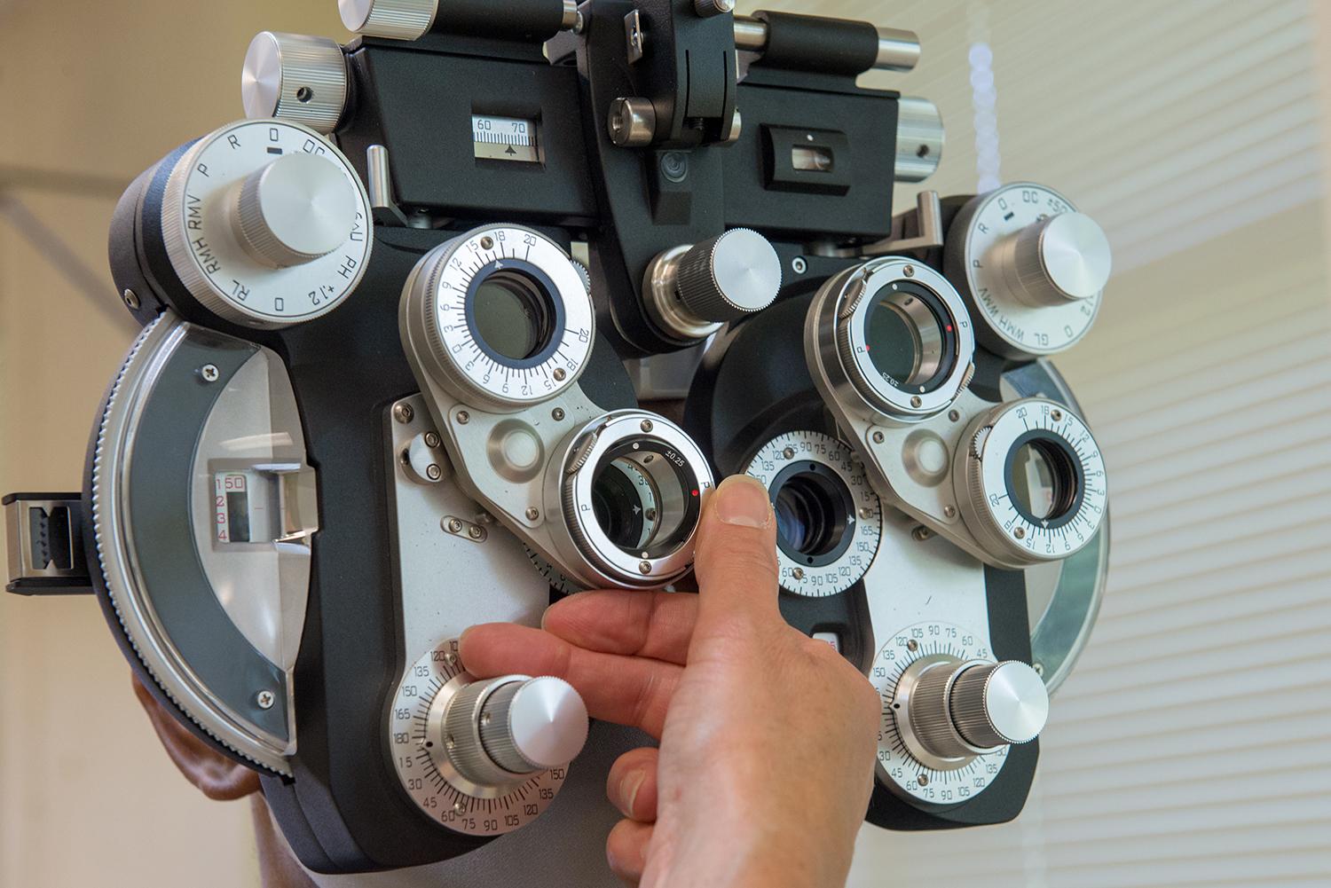 An optometrist adjusts equipment during an eye exam.
