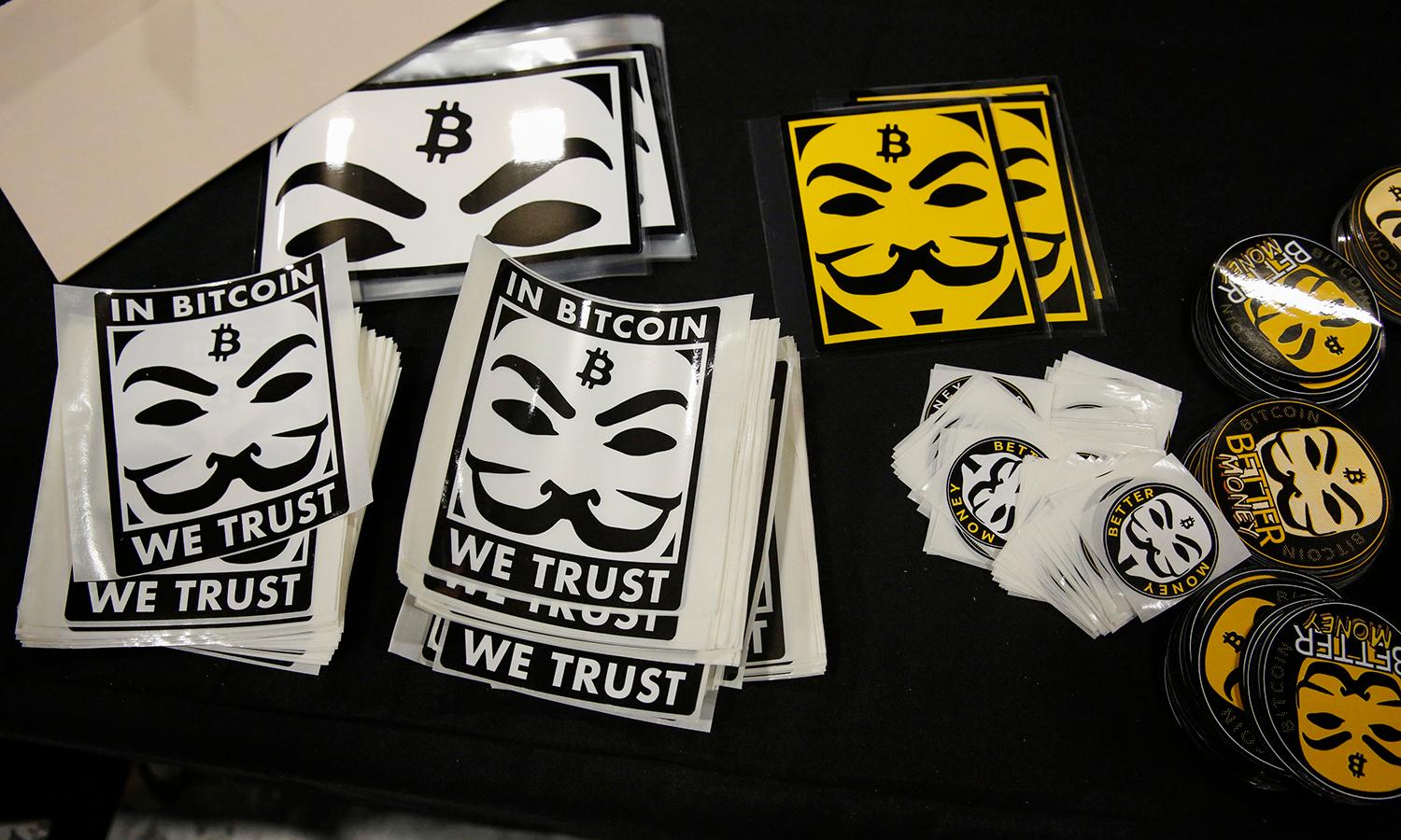 Stickers depicting Guy Fawkes masks (Anonymous mask) and the bitcoin logo are seen at a stand