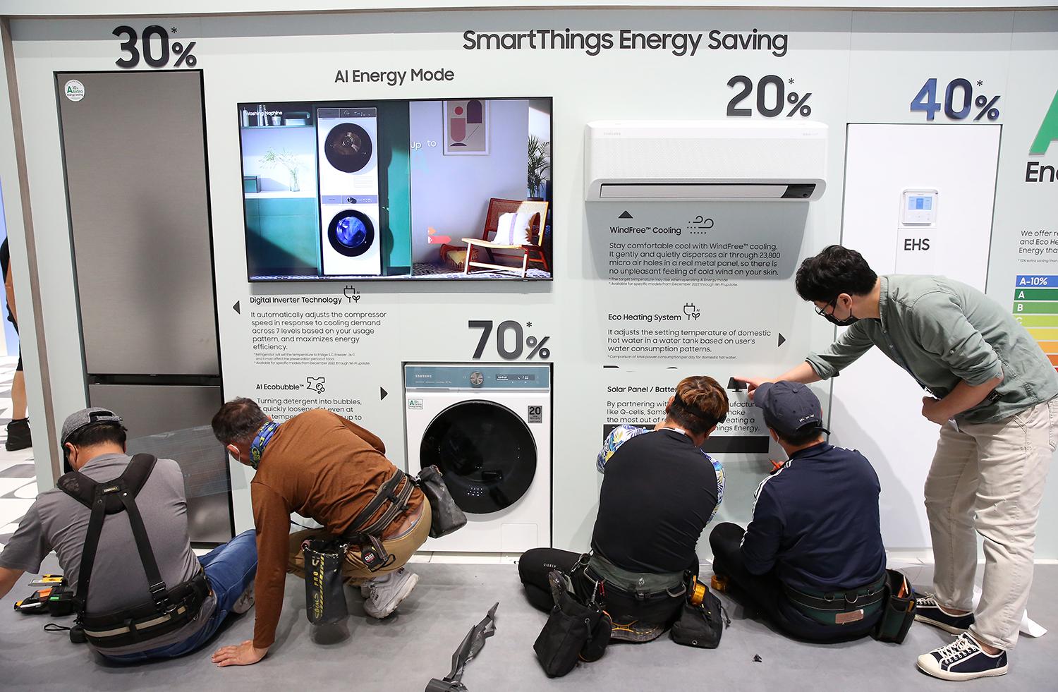 Workers install smart kitchen appliances at a consumer electronics trade show.