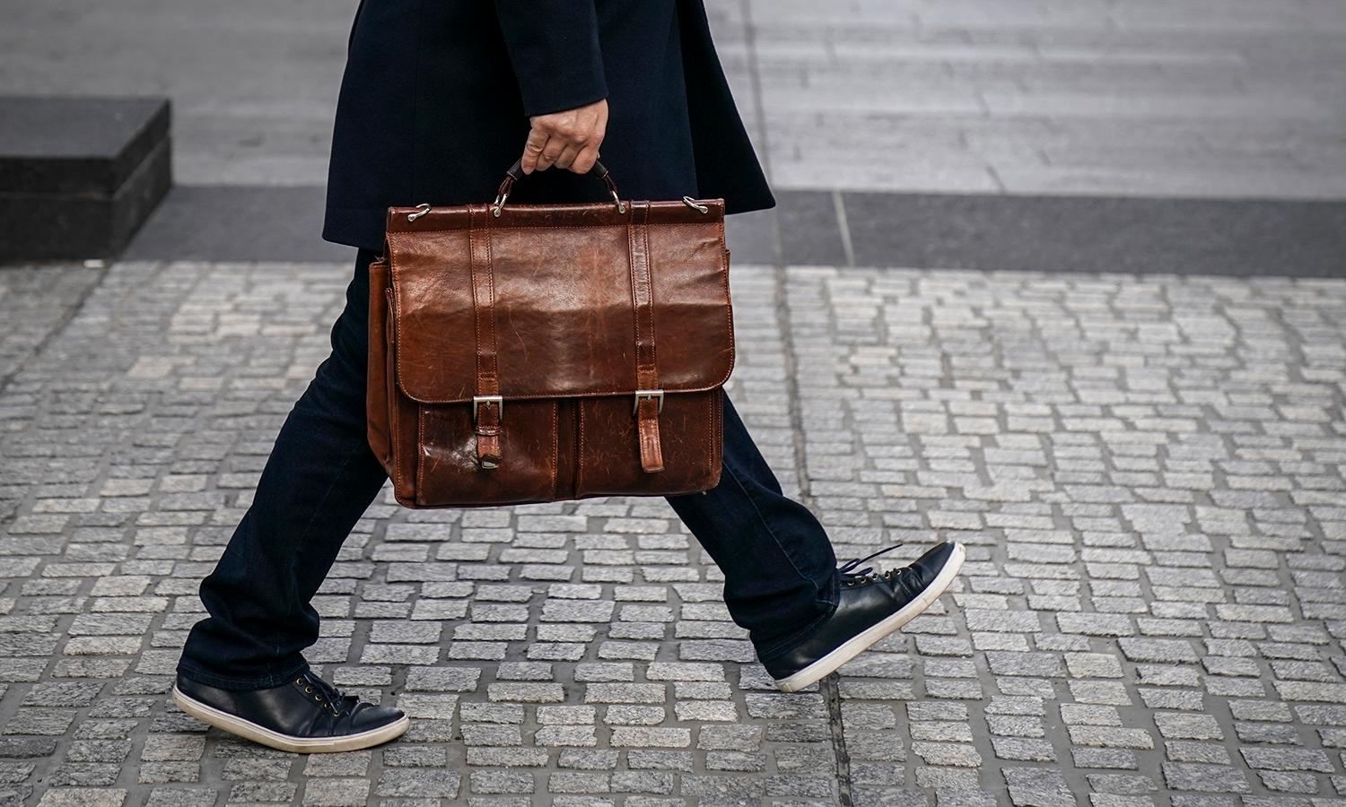 A man carries a briefcase as he walks.)