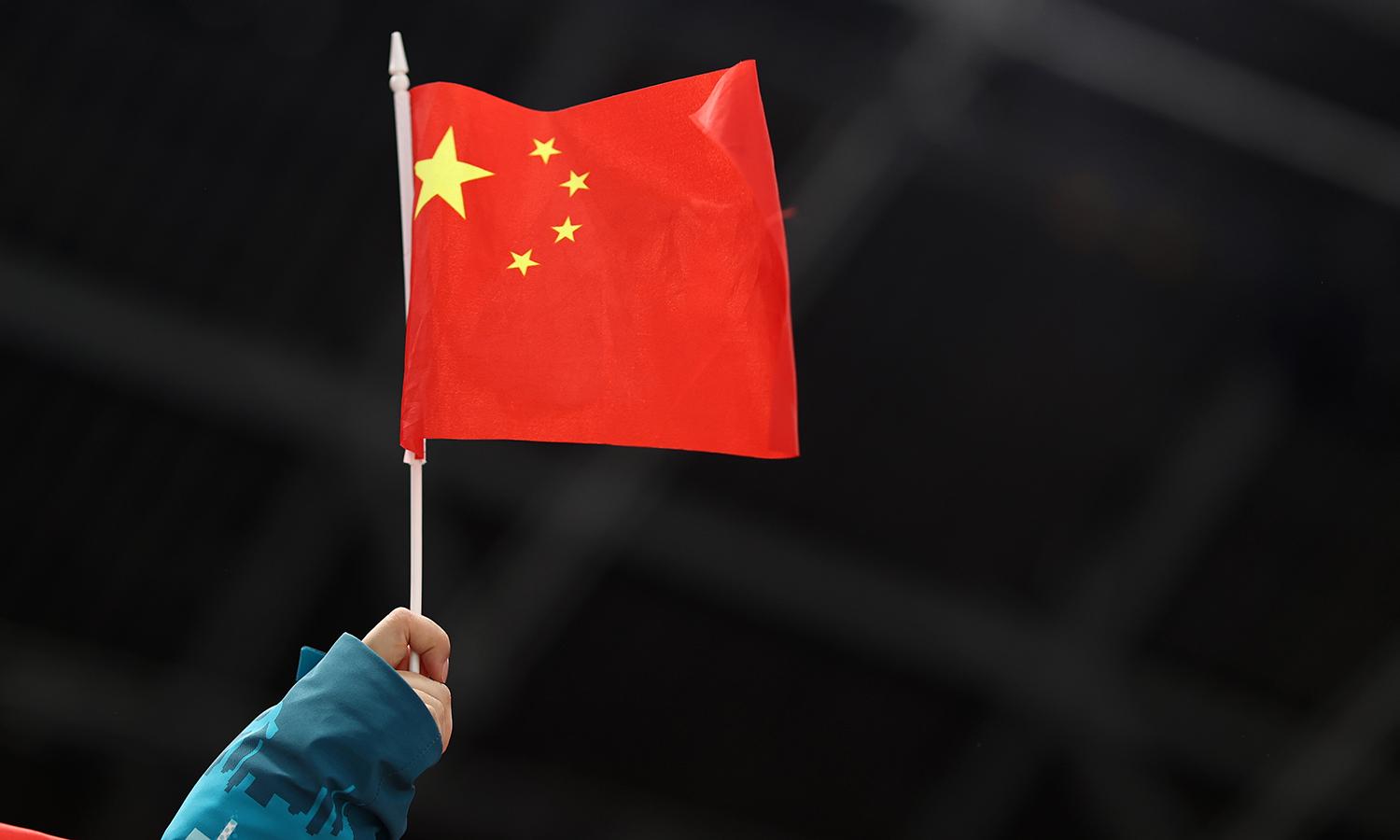 A person holds a small Chinese flag.