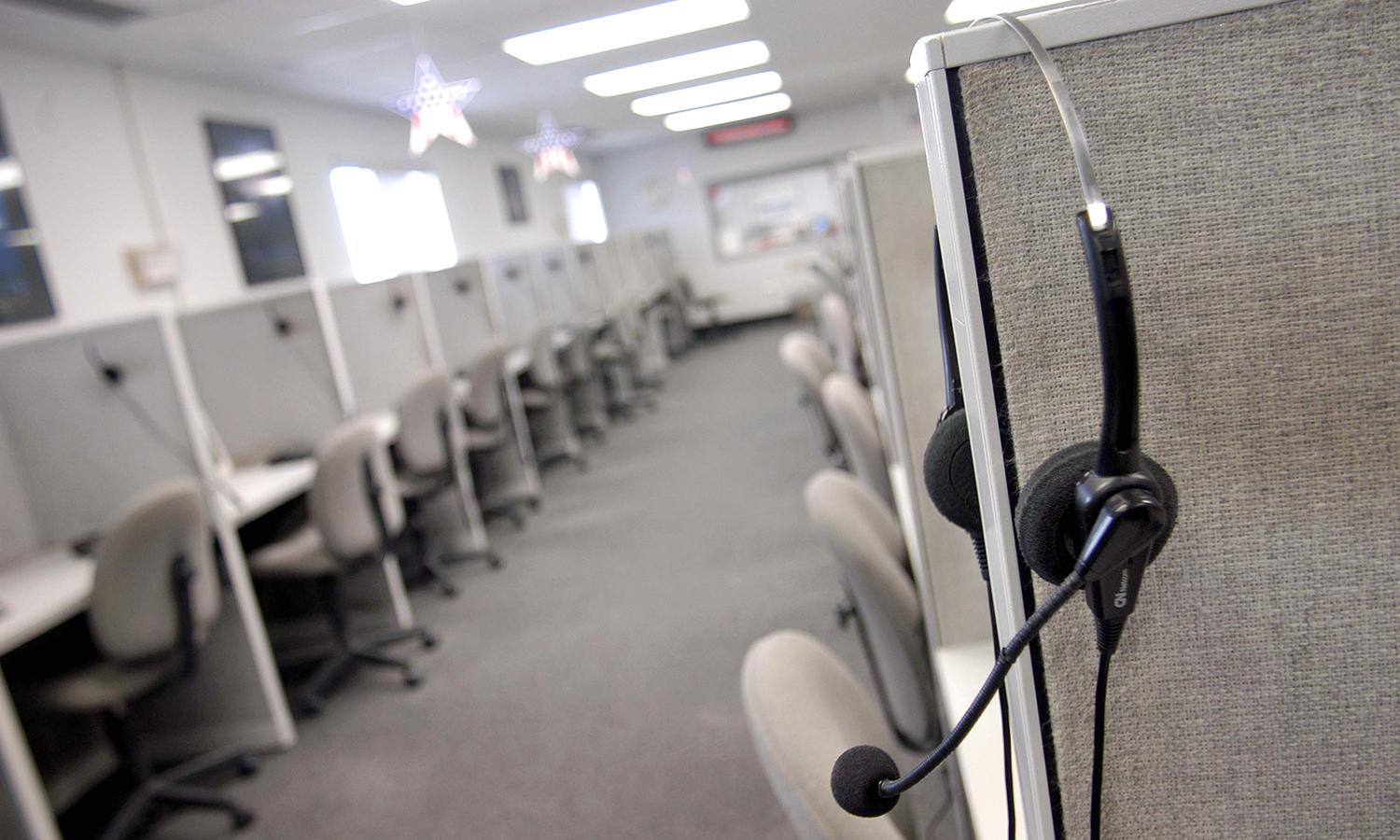 A headset hangs on a cubicle wall