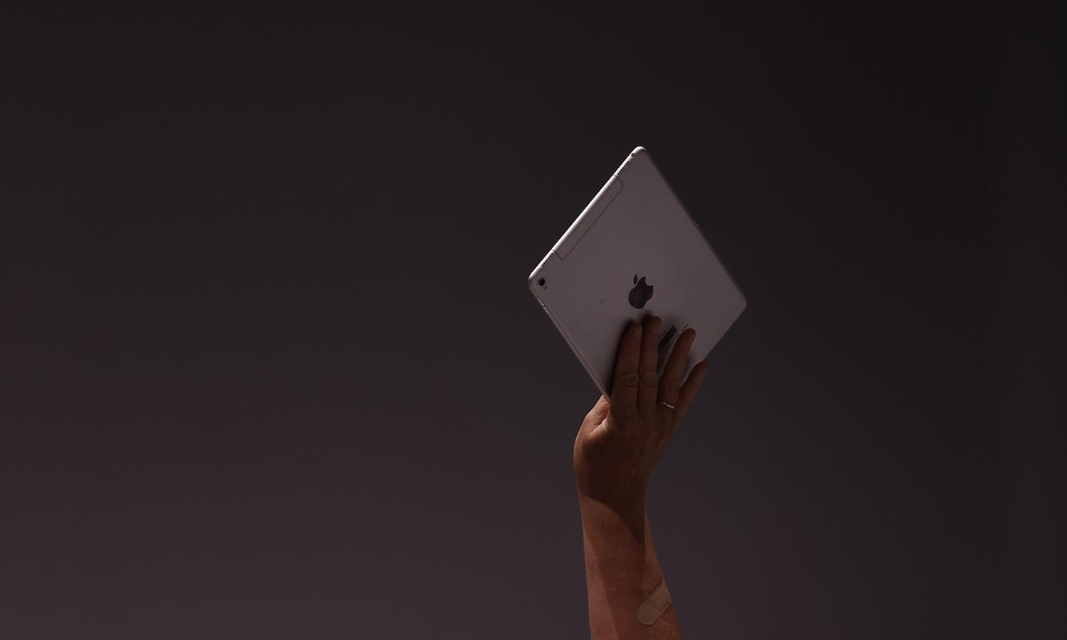 A person holds up an Apple iPad tablet.