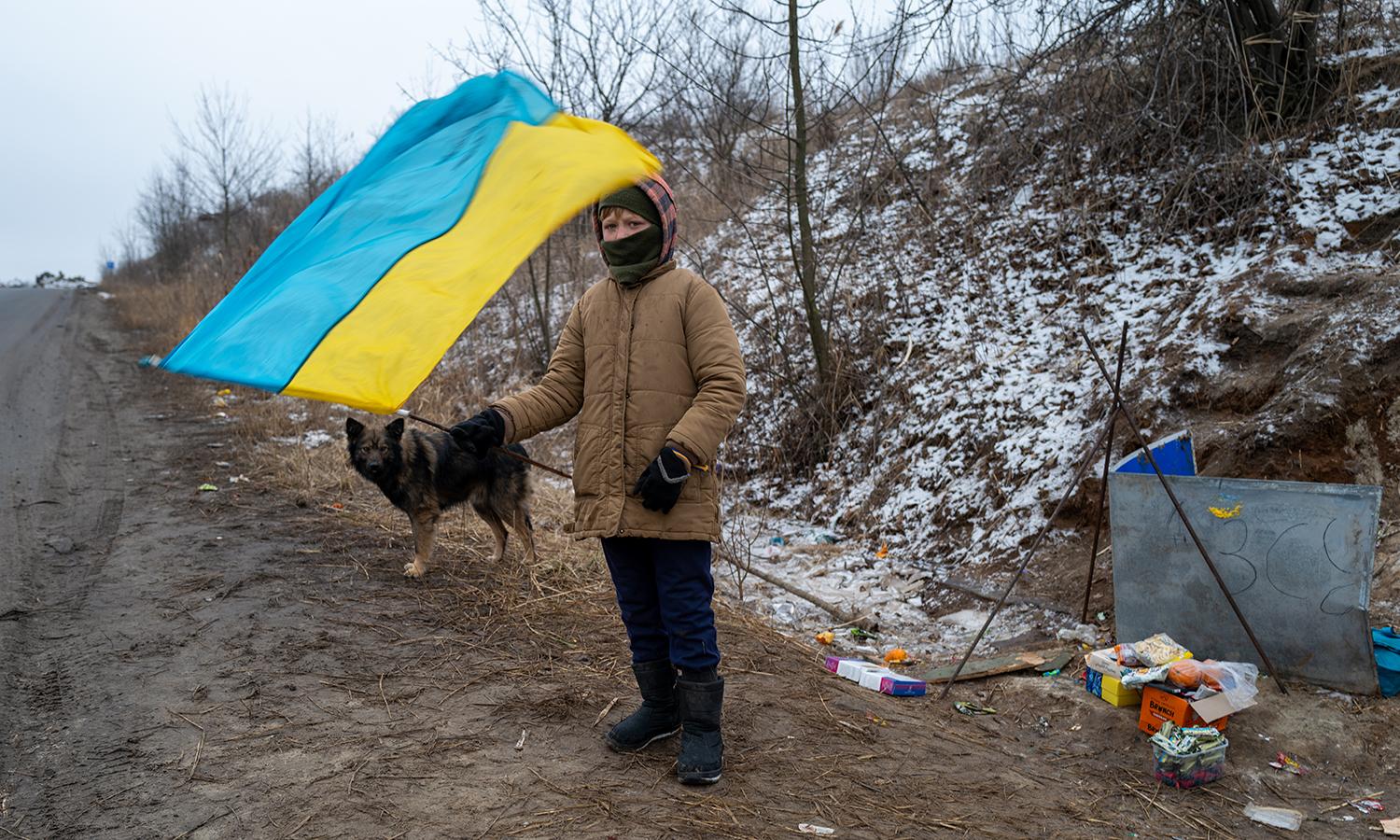 A child waves the Ukrainian flag for passing soldiers