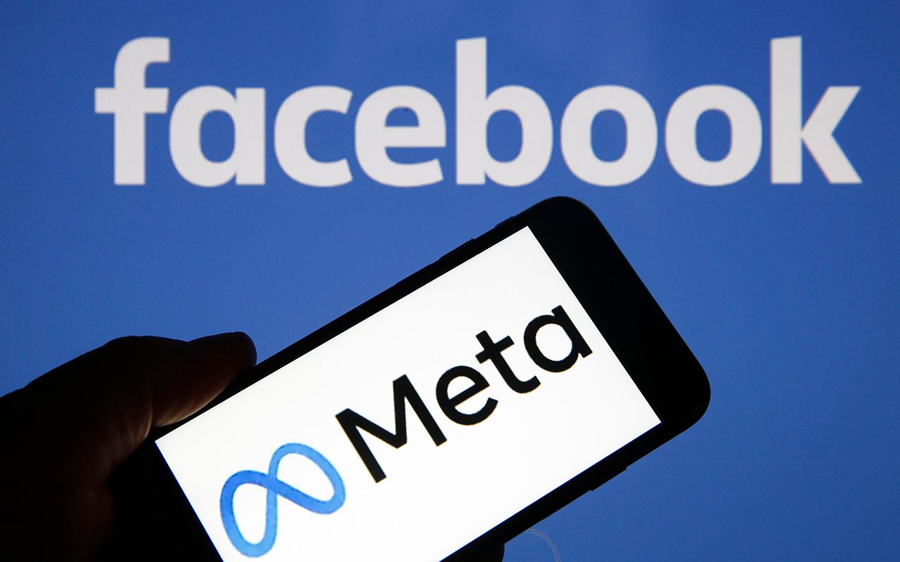 A Meta logo is seen on a smartphone in front of a Facebook logo