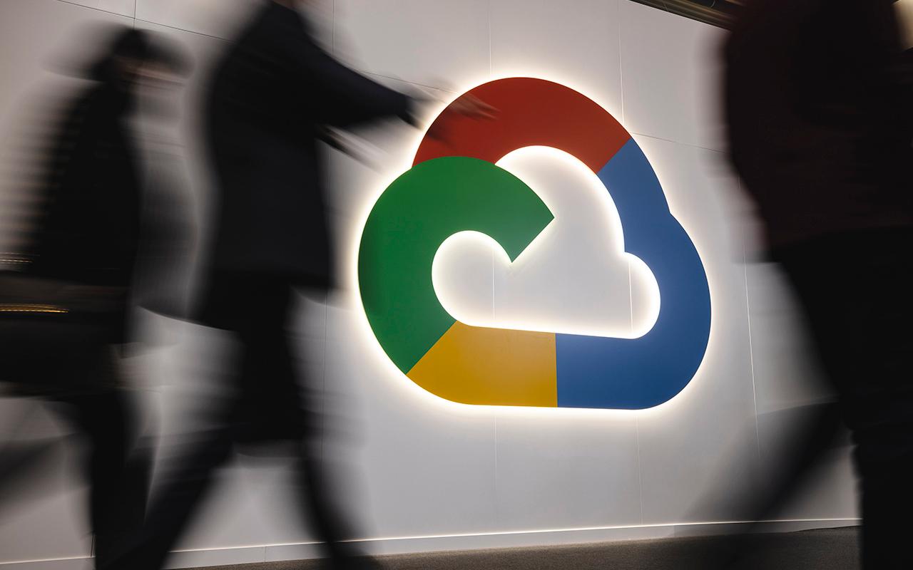 People walk past a Google Cloud logo