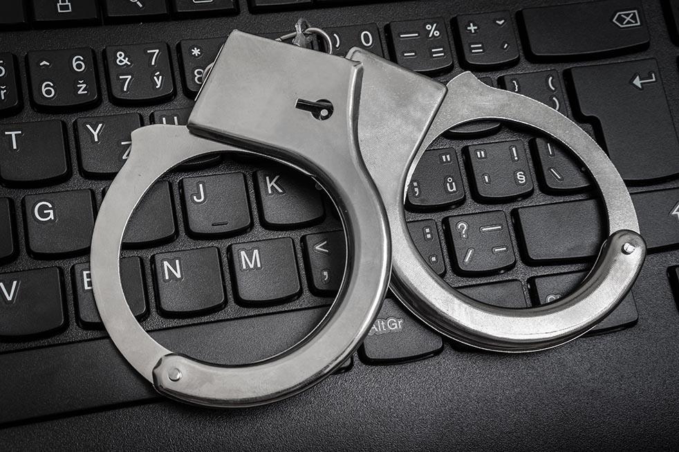 Top view of black keyboard and handcuffs - cyber crime concept